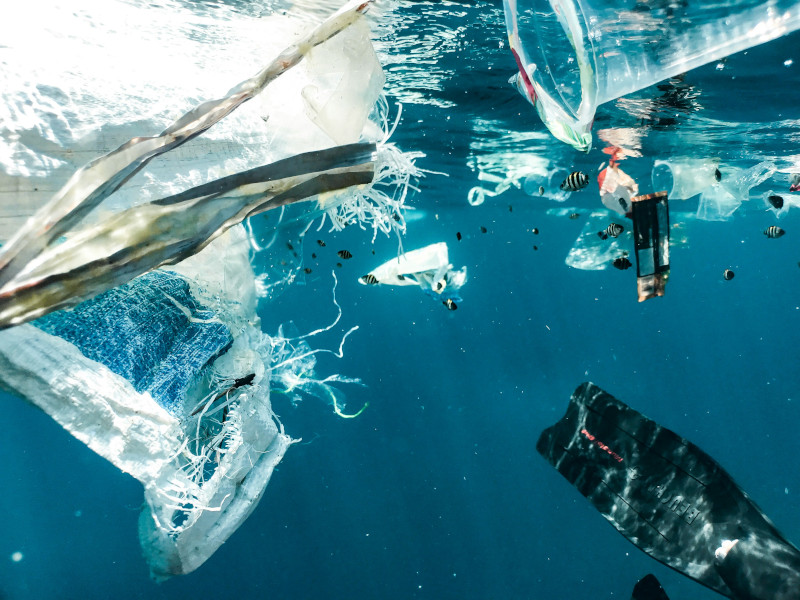 Schwimmender Plastikmüll im Ozean, bestehend aus bunten Fragmenten und Abfallstücken, die sich zwischen den Wellen ausbreiten.